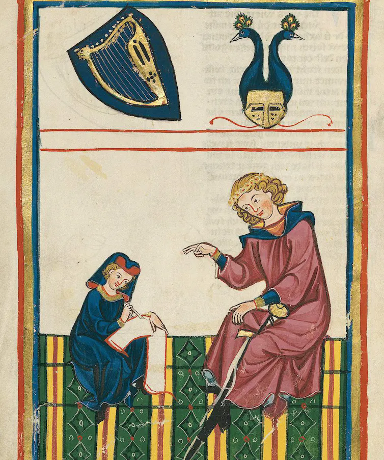 An old manuscript page shows a large figure in a pink robe dictating to a small scribe wearing a blue one.